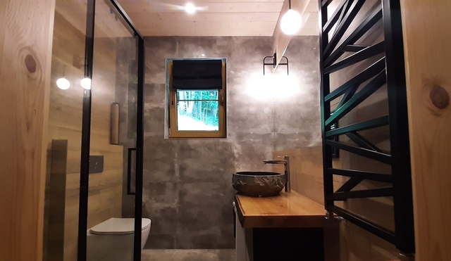 Bieszczady - Domek nad stawem. Łazienka z prysznicem, kamienna umywalka i drewniany blat.