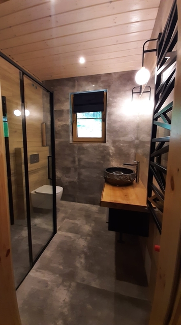 Łazienka z prysznicem - drewniany sufit, wc, drewniany blat z kaminną umywalką.