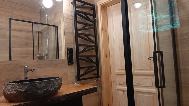 Łazienka - widok na duże lustro, czarny grzejnik i kaminną umywalkę.