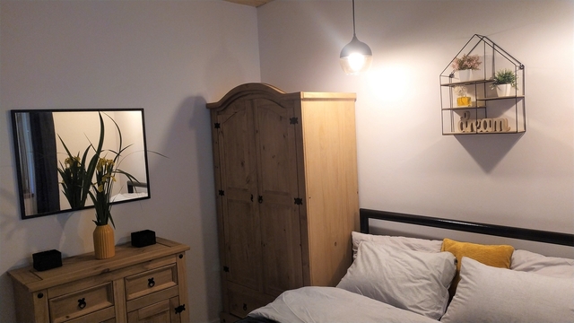 Widok na łóżko, szafę, komodę i lustro.