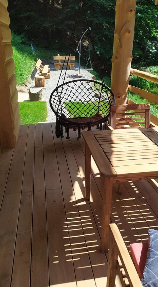 Duży taraz ze stołem, krzesłami i huśtawką. W oddali miejsce na gnisko.