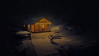 Bieszczady - Domek nad stawem - nocne zdjęcie domku z promieniami światła wylatującego przez okna.